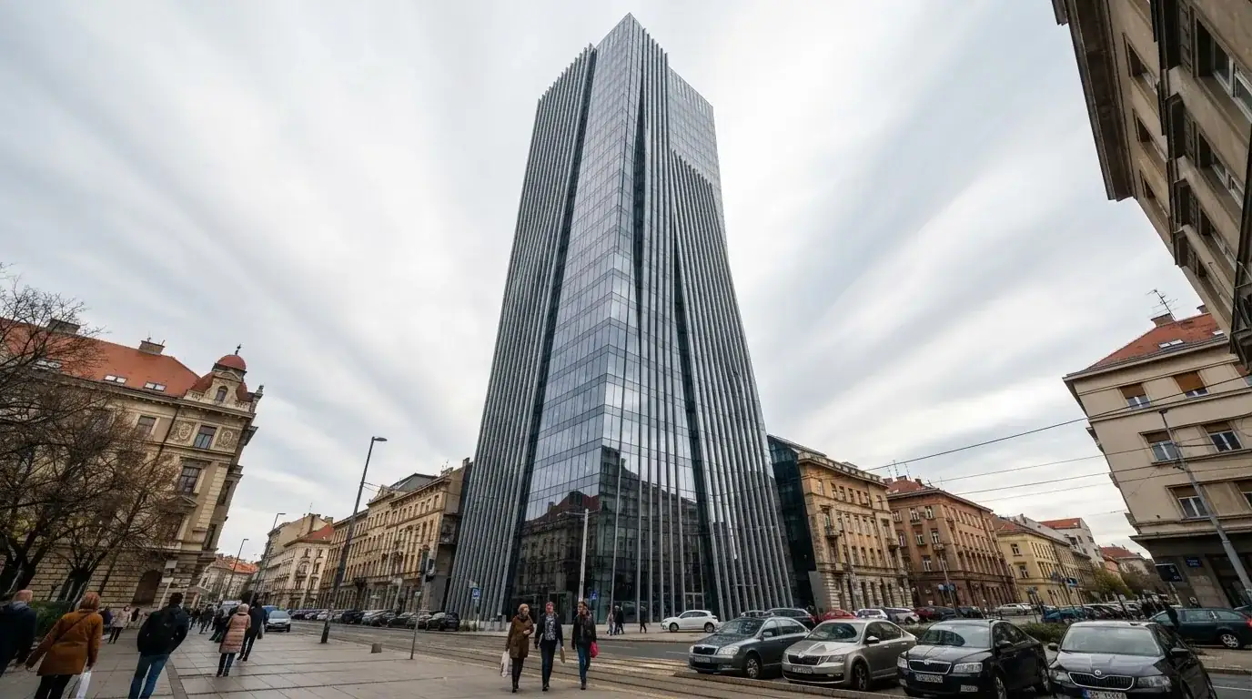 Neboder u središtu Zagreba s odsjajem neba na staklenom pročelju, snimljen s razine ulice.